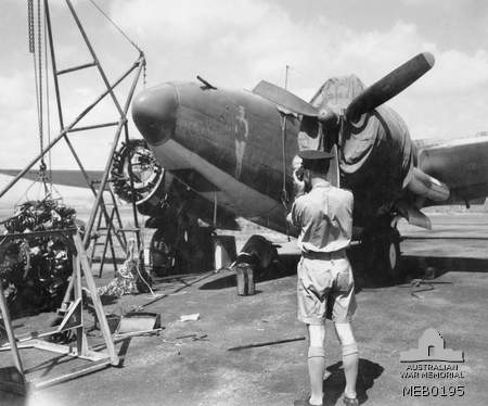 Gambut, Libya. October 1943. Group Captain J. E. Graham, RAAF Liaison Officer, watches the fitters of of No. 459 Squadron RAAF, working on a Ventura aircraft.